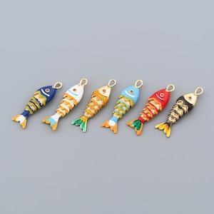 May include: Six colorful fish-shaped charms with gold-tone loops for jewelry making. Each charm features a different color scheme, including blue, white, orange, red, and black, with gold accents. The charms have detailed scales and fins.