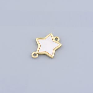 Puede incluir: Un dije en forma de estrella de color dorado con un centro blanco. El dije tiene dos pequeños bucles para sujetarlo a la joyería. La estrella es un diseño de cinco puntas, y los bordes son lisos y redondeados.