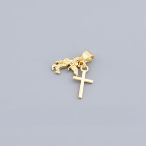May include: A gold-colored pendant featuring a small winged horse and a cross charm. The pendant has a loop for a chain and is set against a gray background. The cross is a simple, classic design.