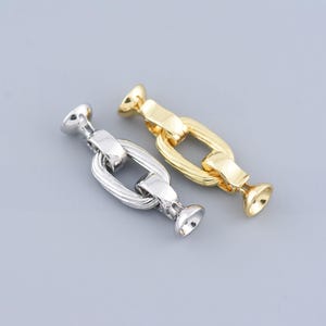 Op de afbeelding: Twee metalen kettingschakels, een gouden en een zilveren, met een afgeronde kant aan elke zijde.