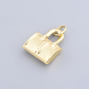 以下が含まれることがあります： ハンドバッグの形をした金色のチャーム。チャームは細部までこだわったデザインで、ネックレスやブレスレットに取り付けるためのループが付いています。