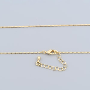 Pode incluir: Um delicado colar dourado com um design de corrente fina. O colar apresenta um fecho lagosta e uma corrente ajustável para um ajuste personalizável. A corrente é feita de pequenas elos retangulares.