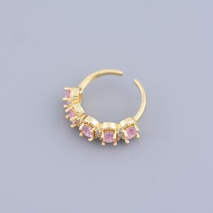 May include: A gold ring with a row of pink gemstones set in a gold band.