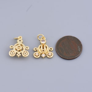 May include: Two gold-tone metal charms in the shape of a carriage with clear rhinestone accents. The charms are about the size of a US penny.