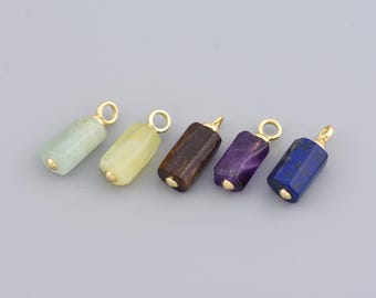 May include: Five gemstone pendants in a row, each with a gold-colored loop at the top. The gemstones are various colors, including green, yellow, brown, purple, and blue. The pendants are cylindrical with rounded ends.