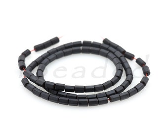 May include: A strand of black square beads, strung on a thin red thread. The beads are matte and have a slightly irregular shape.