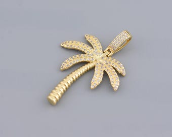 May include: Gold-colored palm tree pendant with clear, sparkling accents. The pendant features a detailed palm tree design with a textured trunk and crystal-like embellishments on the fronds. The bail is also adorned with similar accents.