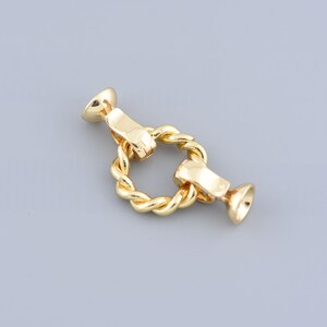May include: Gold-toned metal clasp with a twisted rope design. The clasp has two round ends.