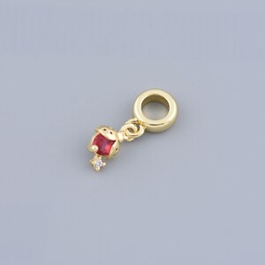 May include: Gold charm with a red and white ladybug design. The charm has a small loop at the top for attaching to a bracelet or necklace.