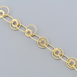 May include: Gold-toned chain necklace featuring a repeating pattern of hexagonal and circular links. The circular links have a twisted rope texture, and the hexagonal links are smooth. The chain is displayed against a gray background.