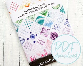 May include: A white booklet with the title "Anything But Basic Rainbow Embroidery Sampler" and a colourful embroidered design on the cover. The booklet is on a white wooden surface. The text "PDF download" is in a circle on the bottom right corner of the image.