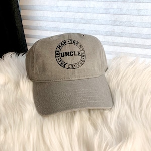 May include: A gray baseball cap with a black embroidered circle that says "The Man, The Myth, The Legend" with "Uncle" in the center.