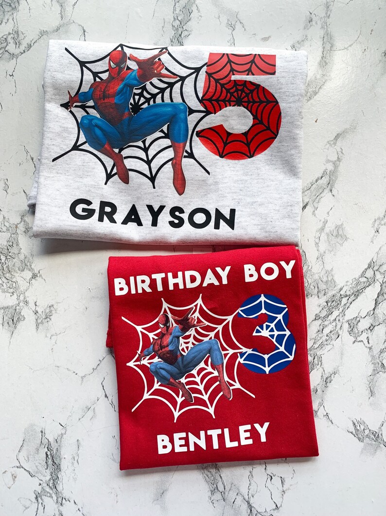 May include: Two red and white t-shirts with a Spiderman graphic and the text "Birthday Boy", "Grayson" and "Bentley".