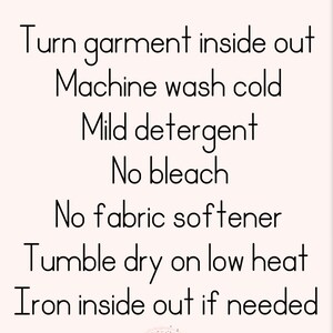 Op de afbeelding: Wasinstructies voor een kledingstuk: Kledingstuk binnenstebuiten keren, koud wassen in de machine, mild wasmiddel, geen bleekmiddel, geen wasverzachter, drogen in de droger op lage temperatuur, binnenstebuiten strijken indien nodig. De tekst "One Inspired Mom" staat onderaan de afbeelding.