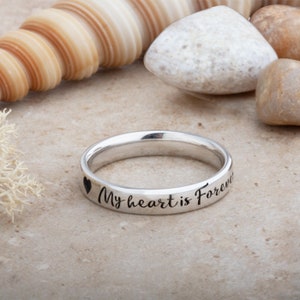 May include: A silver ring inscribed with the words "My heart is Forever" and a small heart symbol.