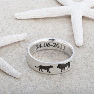 May include: A silver ring with a lion and a leopard engraved on the band. The date 24-06-2017 is engraved on the inside of the ring.