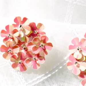 May include: A pair of pink flower-shaped earrings made of sequins. The earrings are on a white background.
