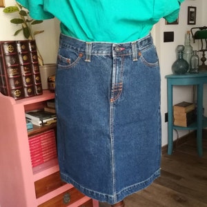 Op de afbeelding: Een donkerblauwe denim rok met een rechte snit en een hoge taille. De rok heeft een knoop- en ritssluiting en vijf zakken.