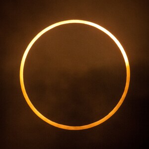 May include: A close-up of a solar eclipse, showing the sun as a bright ring of light against a dark sky.