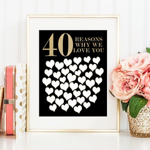 May include: A framed print with a black background and gold text that reads "40 REASONS WHY WE LOVE YOU." The number 40 is large and gold, with 39 white hearts arranged below. The frame is gold, and the print is displayed on a white surface.