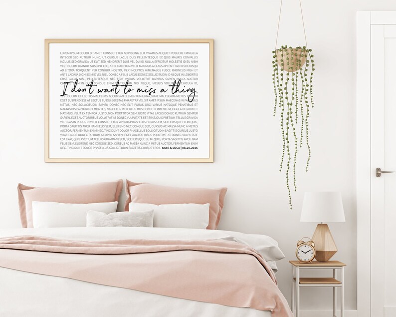 May include: A framed print with a black and white design. The print features a quote that reads "I don't want to miss a thing". The print is hanging on a white wall above a pink bed.