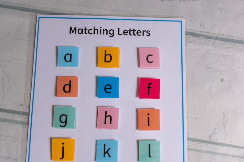 Op de afbeelding: Een witte kaart met de titel "Matching Letters" en 12 gekleurde vierkanten met de letters a tot en met l erop.
