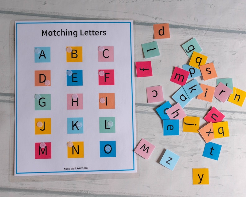 Op de afbeelding: Een kleurrijk alfabet-matchingspel met lettertegels en een raster met de letters A tot en met O. De lettertegels zijn verspreid over een wit oppervlak.