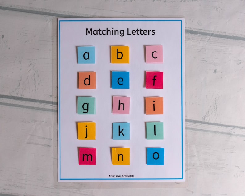 Op de afbeelding: Een kleurrijk educatief matchingspel voor kinderen met de letters van het alfabet, gedrukt op individuele vierkanten papier. De letters zijn gerangschikt in rijen, met elke letter in een andere kleur.