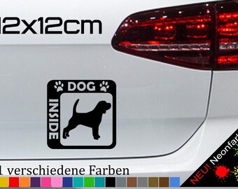 May include: Black and white sticker with a dog silhouette inside a square with the text "DOG INSIDE" and paw prints. The sticker is 12 cm by 12 cm. The text "21 verschiedene Farben" is below the sticker.