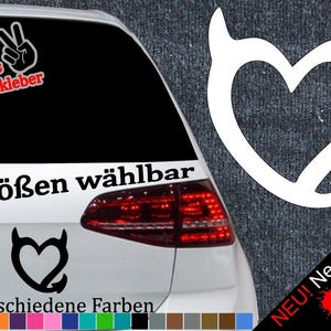 Könnte beinhalten: Ein weißes Auto mit einem schwarzen Herz mit Teufelshörnern Aufkleber auf der Heckscheibe. Der Aufkleber sagt "6 Größen wählbar" und "21 verschiedene Farben".