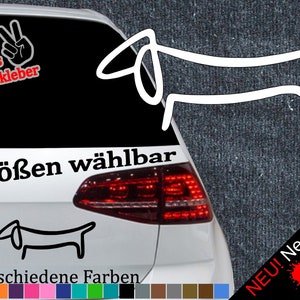 Könnte beinhalten: Ein weißes Auto mit einem schwarz-weißen Dackel-Aufkleber an der Heckscheibe. Der Aufkleber lautet "6 Größen wählbar" und "21 verschiedene Farben". Außerdem befindet sich ein Aufkleber mit einem Peace-Zeichen mit dem Text "+ Gratis Testaufkleber".