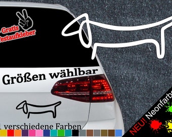 May include: A white car with a black and white dachshund sticker on the back window. The sticker says "6 Größen wählbar" and "21 verschiedene Farben". There is also a sticker of a peace sign with the text "+ Gratis Testaufkleber".