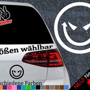 Könnte beinhalten: Ein weißes Auto mit einem schwarz-weißen Aufkleber auf der Heckscheibe. Der Aufkleber zeigt ein Smiley mit Hörnern und den Text "6 Größen wählbar" und "21 verschiedene Farben".
