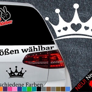 Puede incluir: Coche blanco con una pegatina de corona negra en la ventana trasera. La pegatina tiene corazones. El texto "6 Größen wählbar" está en el coche. El texto "21 verschiedene Farben" está debajo de la pegatina. Hay muestras de colores debajo del texto.