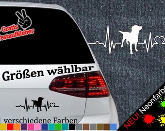 May include: A white car with a black and white dog heartbeat sticker on the back window. The sticker says "6 Größen wählbar" and "21 verschiedene Farben". There is also a sticker with a peace sign and the text "+ Gratis Testaufkleber".