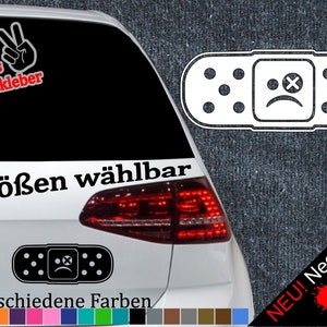 Può includere: Un'auto bianca con un adesivo bianco e nero di un cerotto con un viso triste. L'adesivo dice "6 Größen wählbar" e "21 verschiedene Farben". Ci sono campioni di colore sotto il testo. L'adesivo è sul lunotto posteriore dell'auto. C'è un design di vernice rossa, gialla e verde sul lato destro dell'immagine con il testo "NEU! Neonfarben".