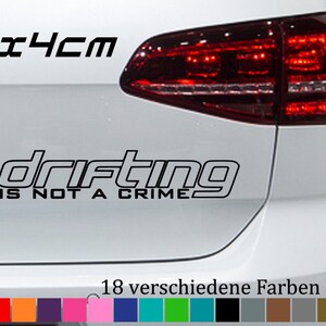 Peut inclure: Une voiture blanche avec un autocollant en vinyle noir qui indique "Drifting is not a crime" et une taille de 20x4cm. L'autocollant est sur le pare-chocs arrière de la voiture. La voiture a un feu arrière rouge. L'image montre également un nuancier de 18 couleurs différentes.