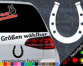 May include: A white car with a black horseshoe sticker on the back window. The sticker says "6 Größen wählbar" and "21 verschiedene Farben". There is a red, white, and blue peace sign sticker on the back window. The sticker also says "+ Gratis Testaufkleber".