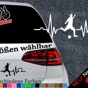 Puede incluir: Adhesivo blanco para coche con un futbolista en acción, integrado en un diseño de línea de latido cardíaco. Texto: "6 tamaños disponibles" y "21 colores diferentes". Texto adicional en alemán.