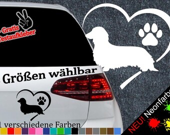 May include: A white car with a black dachshund silhouette inside a heart with a paw print. The text "6 Größen wählbar" is on the car. The text "21 verschiedene Farben" is below the car. The text "+ Gratis Testaufkleber" is on the top left of the car. The text "NEU! Neonfarben" is on the bottom right of the car.