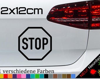 May include: A black and white "STOP" sign decal with an octagonal shape. The decal is 12 inches by 12 inches and is shown on the back of a white car. The text "21 verschiedene Farben" is visible below the decal.