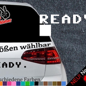 Può includere: Un'auto bianca con un adesivo bianco e nero che dice "READY." L'adesivo è in un font pixelato. L'auto ha anche un adesivo che dice "6 Größen wählbar" e "READY." in testo nero. L'auto ha uno sfondo nero con un segno di pace rosso e il testo "+ Gratis Testaufkleber".