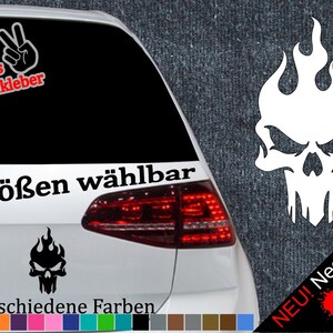 May include: White skull with flames decal sticker for a car. The sticker is available in 6 sizes and 21 colours. The text on the sticker says "6 Größen wählbar" and "21 verschiedene Farben".
