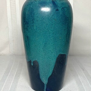 Könnte beinhalten: Eine tealblaue Keramikvase mit einem dunkelblauen Überzug, der an den Seiten heruntertropft. Die Vase hat eine glatte, strukturierte Oberfläche.