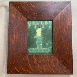May include: A framed green tile with a white candle and the text "GRUEBY TILE" in white.