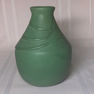 May include: A green ceramic vase with a rounded body and a narrow neck. The vase has a textured surface with swirling lines.