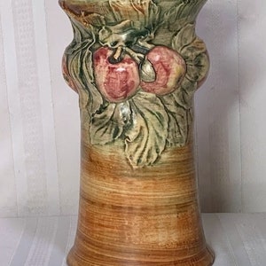 Könnte beinhalten: Eine Keramikvase mit brauner und grüner Glasur. Die Vase ist mit einem erhabenen Design aus Blättern und Äpfeln verziert. Die Vase ist etwa 25 cm hoch.