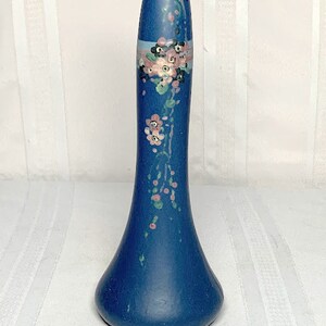 Puede incluir: Un jarrón de cerámica azul con un diseño floral en rosa, azul y verde. El jarrón tiene un cuello estrecho y una base ancha.
