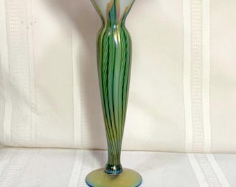 May include: A tall, iridescent glass vase with a flared top and a slender, green-striped stem. The vase has a wide, circular base and measures approximately 12 inches in height. The top and base have a golden sheen.