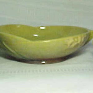 Puede incluir: Un juego de tres piezas de cerámica esmaltada verde y marrón. Un cuenco en forma de corazón con dos candelabros a juego.